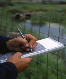 Man taking notes while standing in a riparian area